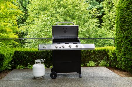 Outdoor cooker with lid in open position on home patio